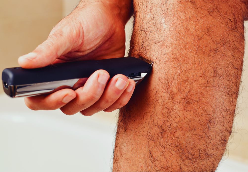 Cordless body clipper trimming hair on a man's leg